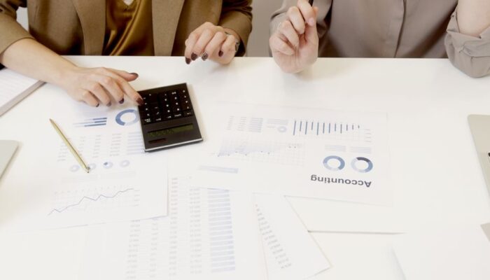 Two professionals analyzing financial documents with a calculator. - Photo by Artem Podrez on Pexels