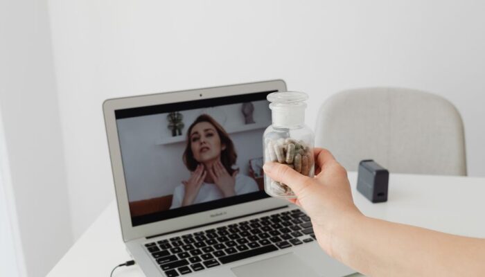 Person holding supplements during a virtual consultation with a doctor on a laptop. - Photo by https://kaboompics.com/ on Pexels