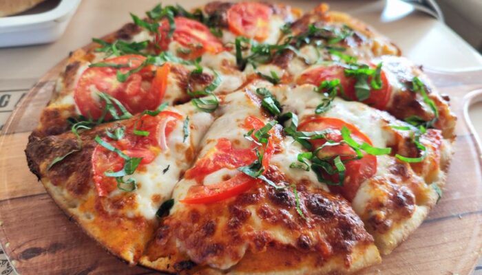 Close-up of a fresh Margherita pizza with tomatoes and basil. Perfect for Italian cuisine promotions. - Photo by Sonali Mehta on Pexels